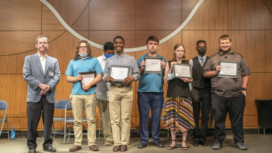 The Class of 2022 Project SEARCH graduates hold up their Certificates of Completion just after the conclusion of their graduation ceremony at UAMS. Chancellor Cam Patterson, left, also spoke at the event.