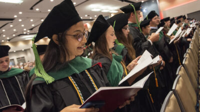 Newly robed graduates recite the Hippocratic Oath in unison.