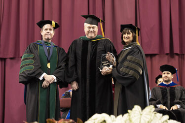 Gregory Snead, center, receives the Chancellor's Award for Teaching Excellence from Chancellor Cam Patterson, left, and Provost Stephanie Gardner.