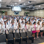 The Physician Assistants Class of 2024 stands to recite and take the Professional Oath on May 27 in the Smith Auditorium.