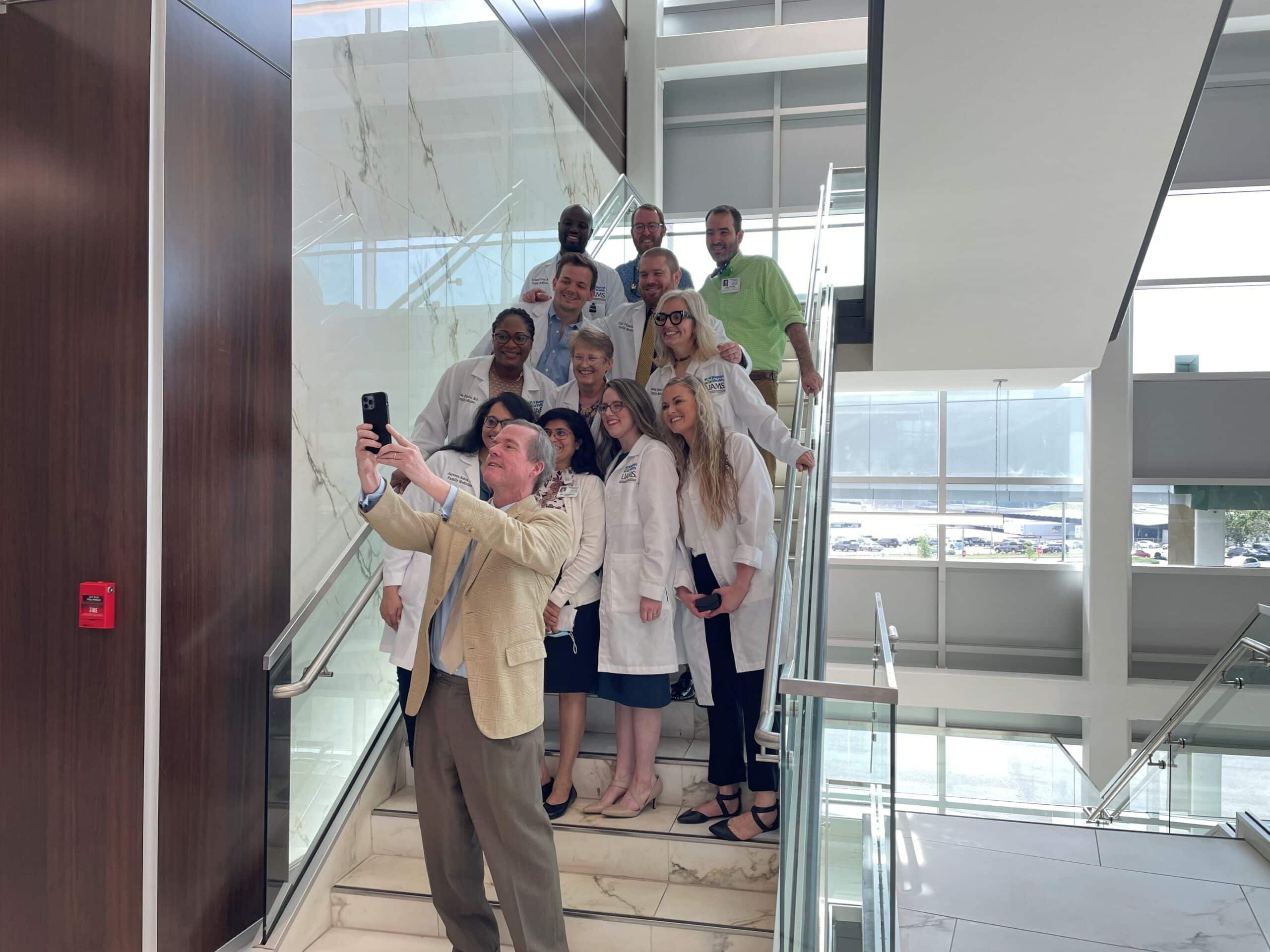 Chancellor Cam Patterson takes a photo with graduating residents at the Baptist Health Medical Center-North Little Rock campus.