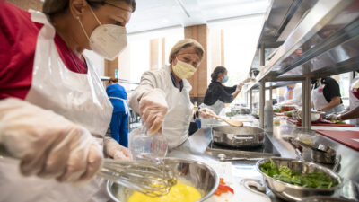 Rebecca Smith, left, and Dees Davis, right, cook a frittata during a workshop in late June in the UAMS Culinary Medicine Kitchen.
