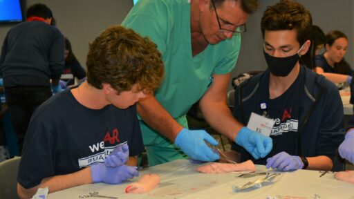 High school students learn suture techniques on pig feet at the UAMS MASH summer camp.