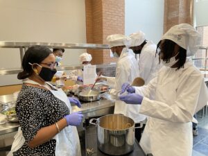 Shanea Nelson (left), executive director of the Pathways Academy program, helps students make spaghetti and meat sauce in the Culinary Medicine Kitchen at UAMS. 