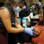 Beatriz Mondragon with the Arkansas Minority Health Commission provides a health screening for Marcovous Williams during the UAMS Midsouth Black Expo.