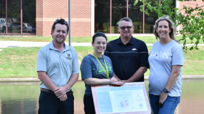 UAMS and city of Springdale officials stand near one of the podium displays along the city's new StoryWalk.