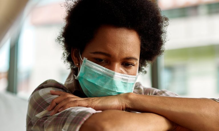 woman wearing surgical mask with arms crossed