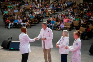 A student (from left) receives congratulations from Fermin Renteria, director of the BSN program; Patricia Cowan, dean of the College of Nursing; and Teresa Whited, associate dean for academic programs.