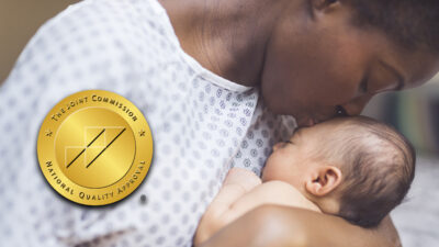 stock image of mother in hospital gown holding newborn baby