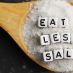 Salt in spoon with the words "Eat Less Salt"