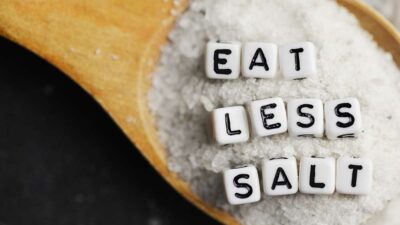 Salt in spoon with the words "Eat Less Salt"