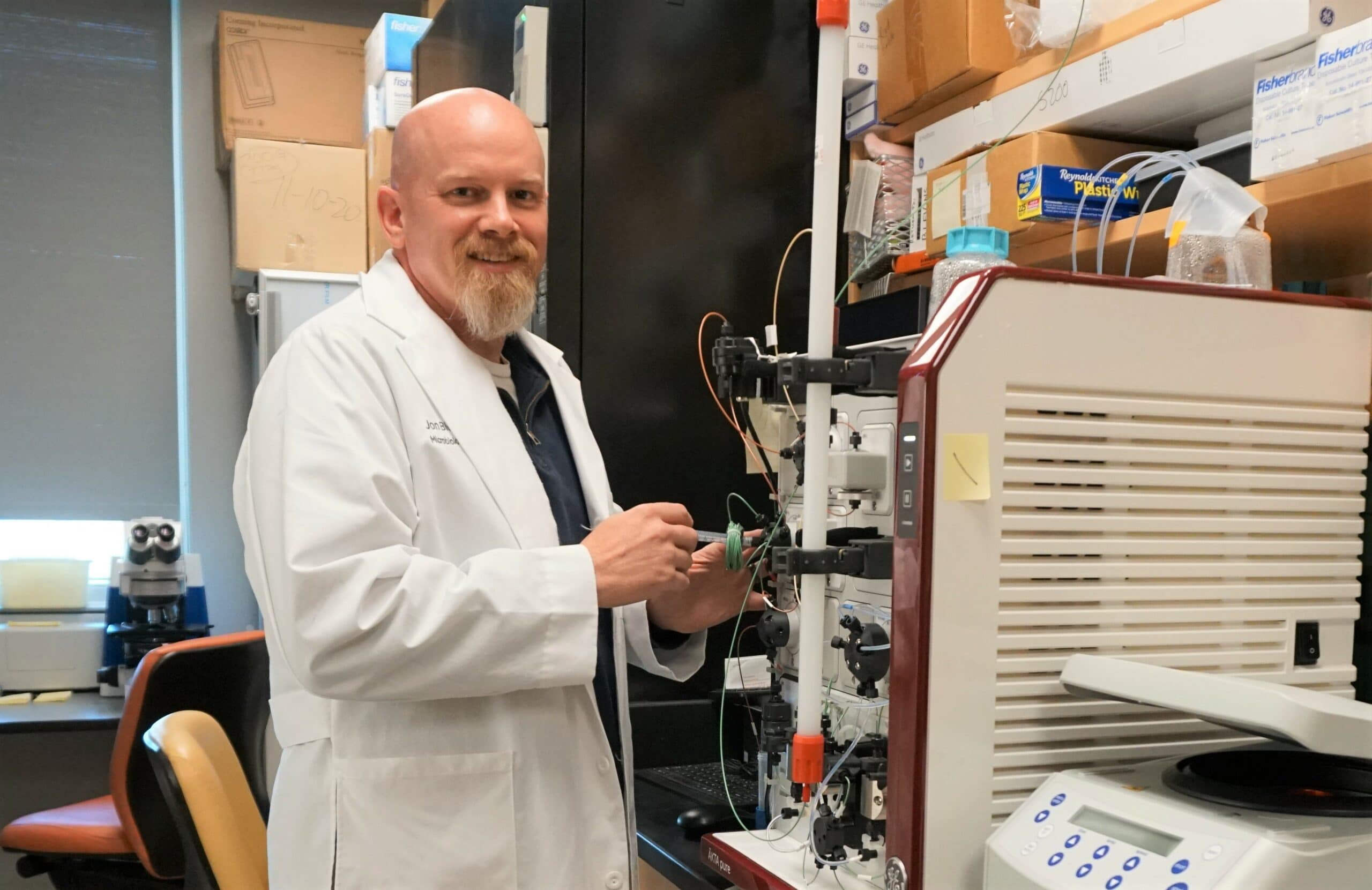 Jon Blevins, Ph.D., in his lab with a Cytiva ÄKTA pure chromatography system used for purification of proteins in his research of tick-borne relapsing fever.