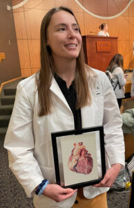 Student Alexa Pearce holds her framed watercolor painting after the ceremony.