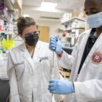 A student in the Health Career University program receives help with his work in a UAMS laboratory.