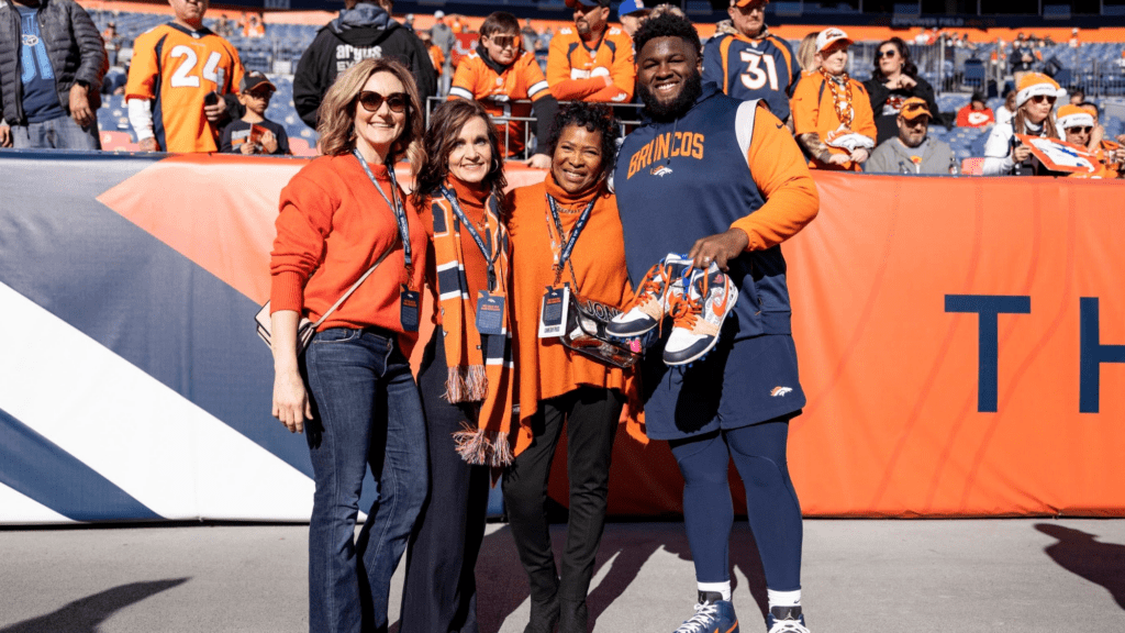 A professional football player with the Denver Broncos team stands with his mother and two nurses