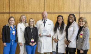 Surrounding J.D. Day, M.D., holding trophy, are (from left to right) Ashley Benton, R.N.; M.J. Orellano, neurosurgery service line administrator; Gaye Sink, R.N.; Analiz Rodriguez, M.D., Ph.D.; Ebonye Green, A.P.R.N.; and Cynthia Brown, R.N.