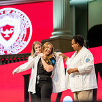 A student in the Bachelor of Science in Nursing program dons her white coat during a ceremony in October.