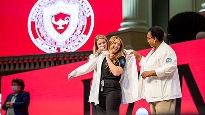 A student in the Bachelor of Science in Nursing program dons her white coat during a ceremony in October.