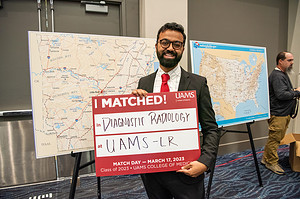 Dhruba Dasgupta , who matched to a diagnostic radiology residency at UAMS, stands before maps showing the locations in Arkansas and across the United States where students matched.