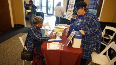 Crystal Crosswell from the Winthrop P. Rockefeller Cancer Institute, assists Thelma Shorter, who signed up to receive a colorectal screening kit.