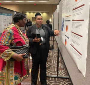 Genesis Jackson describes her research to an attendee at the Health Disparities Conference.
