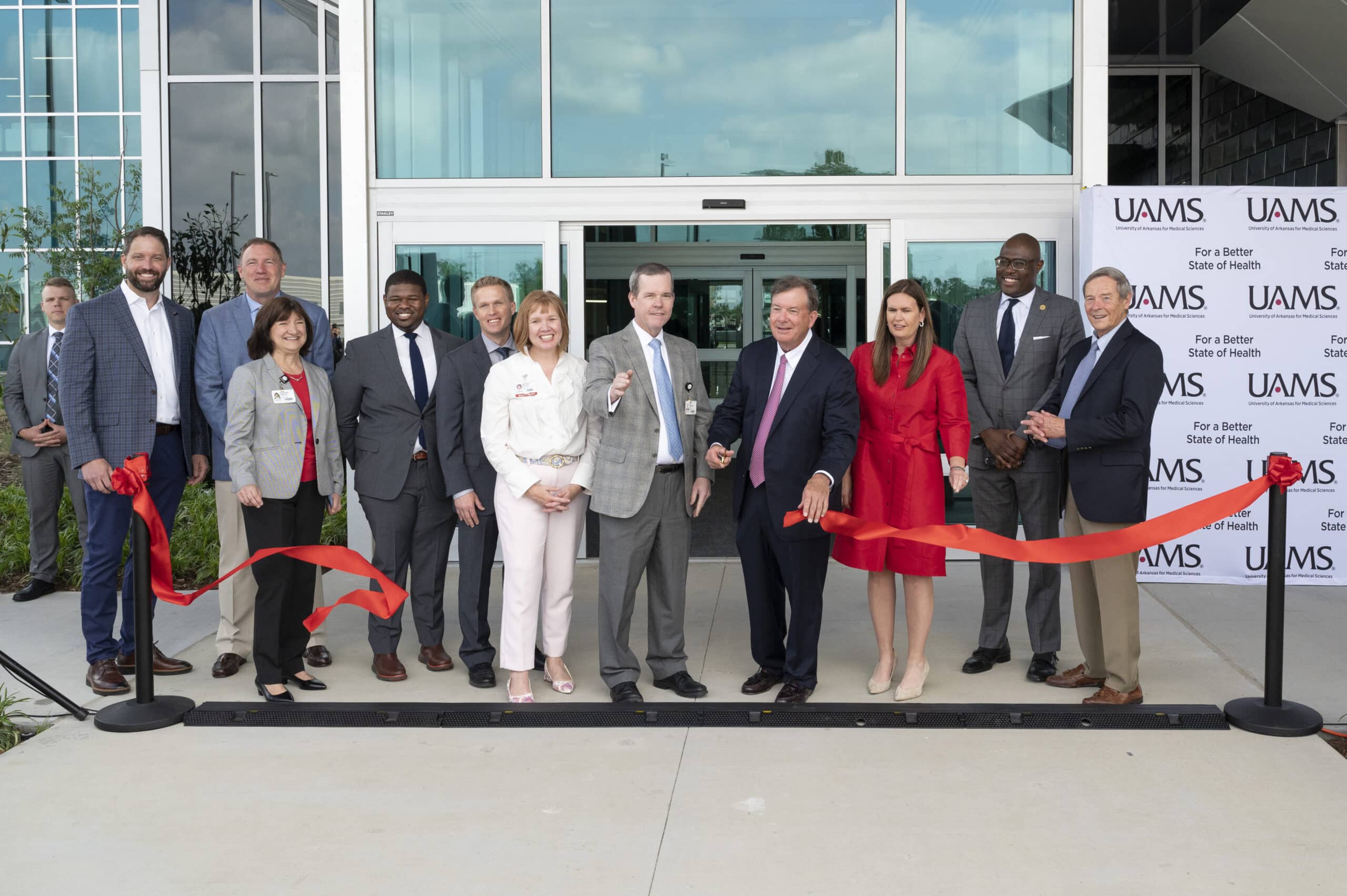 Smiles abound as C. Lowry Barnes, M.D., chair of the Department of Orthopaedic Surgery, flanked by Chancellor Cam Patterson, M.D., MBA and Gov. Sarah Huckabee Sanders, cuts the ribbon in front of The Orthopaedic & Spine Hospital. Also pictured (from L-R) Jake Nabholz, CEO of Nabholz Construction; Greg Cockman, CEO of Cromwell Architects Engineers; Stephanie Gardner, Pharm.D., Ed.D., UAMS senior vice chancellor for Academic Affairs, provost and chief strategy officer; Johnathan Goree, M.D., UAMS director of Interventional Pain Management Services; Paul Stover, UAMS assistant vice chancellor for Clinical Administration; Michelle Krause, M.D., senior vice chancellor for UAMS Health and CEO, UAMS Medical Center; Patterson; Barnes; Huckabee Sanders; Little Rock Mayor Frank Scott Jr.; and Morril Harriman, chair of the U of A System Board of Trustees.