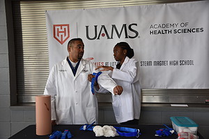 Avi Bhavaraju, M.D., associate professor in the Department of Surgery-Division of Trauma and Acute Care Surgery, works with a student during a trauma-care demonstration at Hall High. 