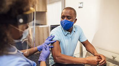 Senior Man Receiving COVID-19 Vaccine From Nurse