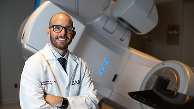 UAMS Radiation Oncology Adam Wolfe standing in front of a radiation machine in the new UAMS Radiation Oncology Center