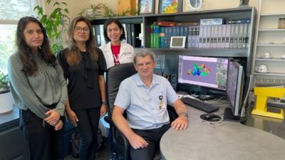 Vladimir Lupashin, Ph.D., at his desk surrounded by his team of graduate assistants. Standing from left to right: Amrita Khakurel, Farhana Taher Sumya and Zinia Dsouza