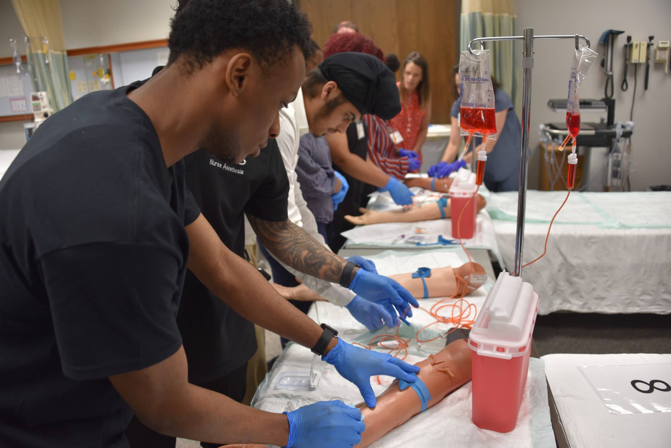 Students in the Pre-Nursing Summer Scholars program use manikin arms to practice blood-draw techniques.