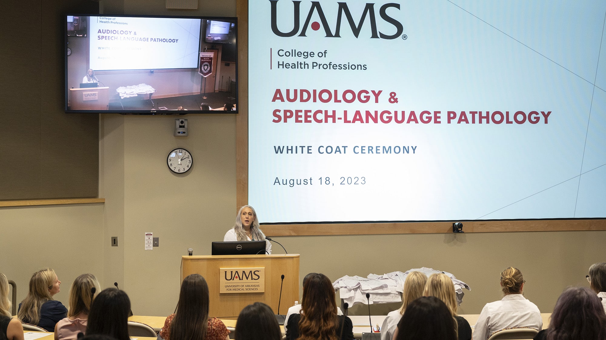 Dana Moser speaks and formally begins the Audiology & Speech-Language Pathology White Coat Ceremony in an auditorium of the I. Dodd Wilson Building on the UAMS Little Rock campus.