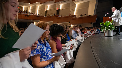 Incoming medical students, known as the Class of 2027, recite the medical student oath before donning their white coats on stage.