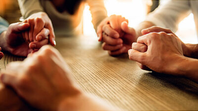 People holding hands around a table