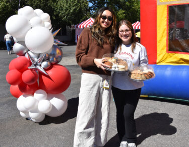 Brittany Tian, left, and Nadia Safar, right, stand in front of the bounce house at the festival and get ready to offer cookies to some of the volunteers at the celebration.