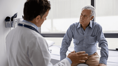 Older white man in a medical clinic speaking to a doctor