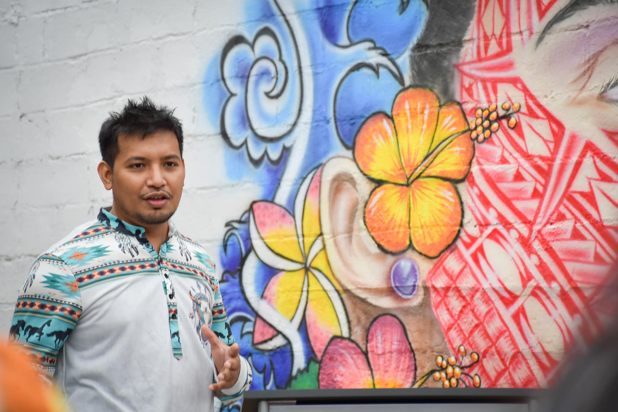 Artist Helmar Anitok talks about his mural during the unveiling in downtown Springdale.