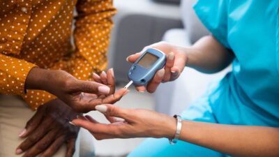 Nurse giving a patient a blood sugar level test