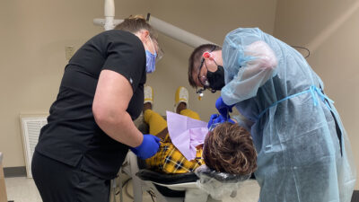 A resident dentist and dental hygienist treat a patient at the UAMS 12th Street Center for Health & Wellness.