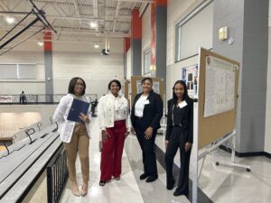 Students stand near their research posters during the symposium in Hall STEAM Magnet High School’s Cirks Arena.