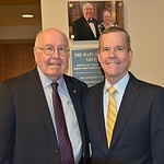Reed Greenwood and UAMS Chancellor Cam Patterson stand in front of the sign dedicating the UAMS Northwest Campus vice chancellor's office as the Mary Ann and Reed Greenwood Office of the Vice Chancellor
