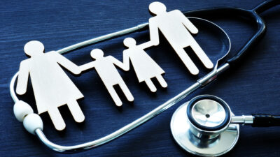 Stock image of figures of a family and stethoscope on navy background.
