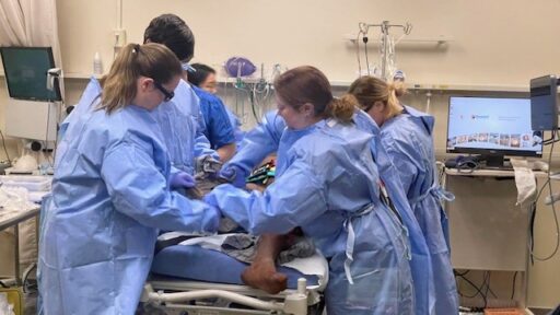 Interprofessional students assess a patient who was just wheeled in.