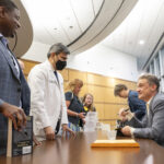 Johnathan Goree, M.D., left, who directs Interventional Pain Management Services at UAMS, and Rohit Dhall, M.D. , chair of the UAMS College of Medicine Department of Neurology, talk with Keefe while he signs copies of his books after the lecture.
