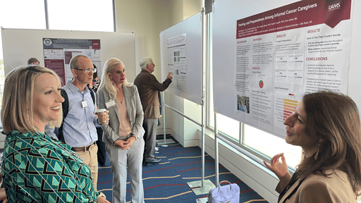 UAMS cancer researchers talk about a study displaying on a poster in front of them