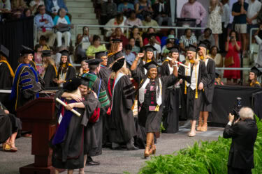A graduate celebrates onstage after receiving her diploma during the UAMS commencement ceremony.