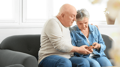 Older couple checking blood sugar levels together on a couch
