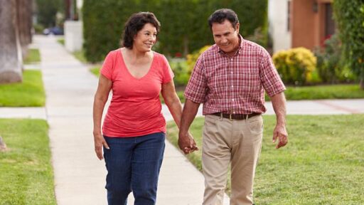 senior Hispanic couple walking and holding hands on sidewalk