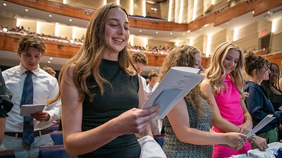 Students stand and read the medical student oath. Upper balconies in background.