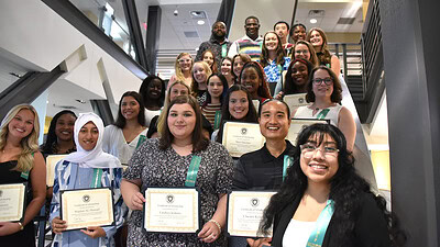 College of Health Professions students hold certificates of scholarship while gathering on the lobby stairs in the Rahn Education Building after a scholarship reception that recognized scholarship donors and student recipients.